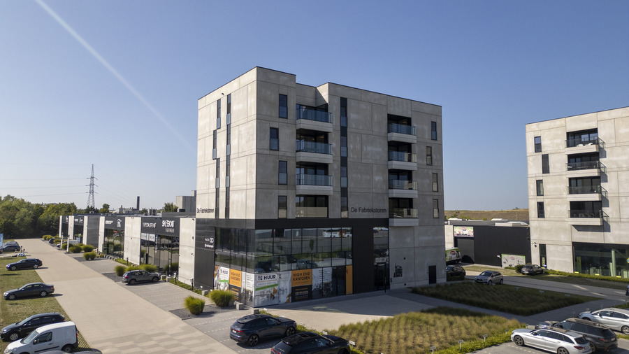 Modern kantoorgebouw met parkeerplaats op zonnige dag.