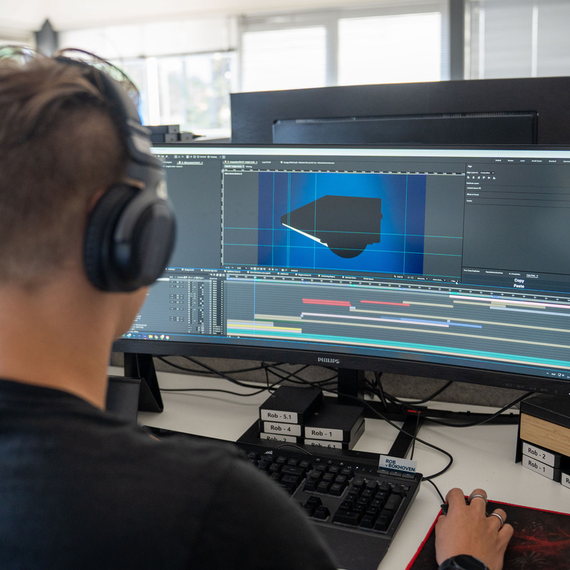 Man werkt aan videobewerking op computer met koptelefoon.